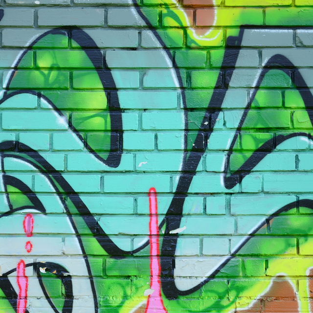 Blue and green graffiti on a brick wall
